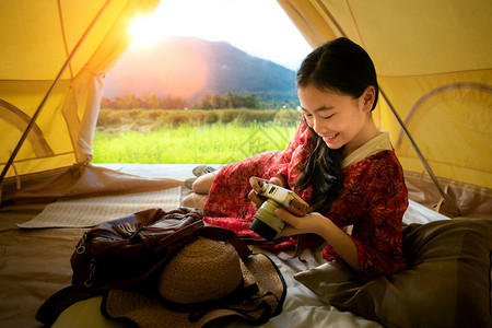 亚裔女孩在泰国南省普阿区稻田的乡间家居帐篷内放松图片