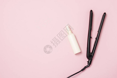 粉红色背景上的直发器和护发产品图片