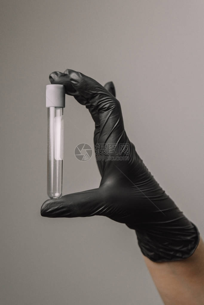 科学家或美容师手中玻璃瓶中的空试管灰色背景上的黑色手套实验图片
