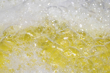 彩虹黄色背景中沐浴水泡沫的特写图片
