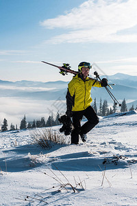 英俊的滑雪者拿着棍子和滑雪靴在山上行走图片