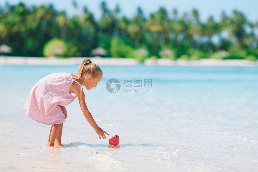 可爱的小女孩玩具在海滩上玩具图片