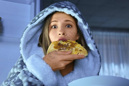 女孩在晚上在冰箱附近吃不健康食物时被抓图片