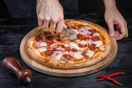 用意大利腊肠肉火腿香肠辣椒番茄奶酪在黑色背景的木板上用比图片