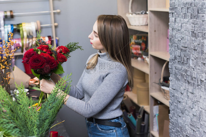 一个漂亮的女孩在她的工作室里收集了一束深色的勃艮第红玫瑰男花店在花店里创造美丽的花束鲜花递送创建订图片