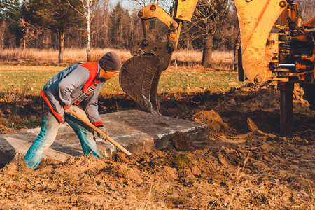 铲子工人在挖掘土机后清理土壤铺设道路图片