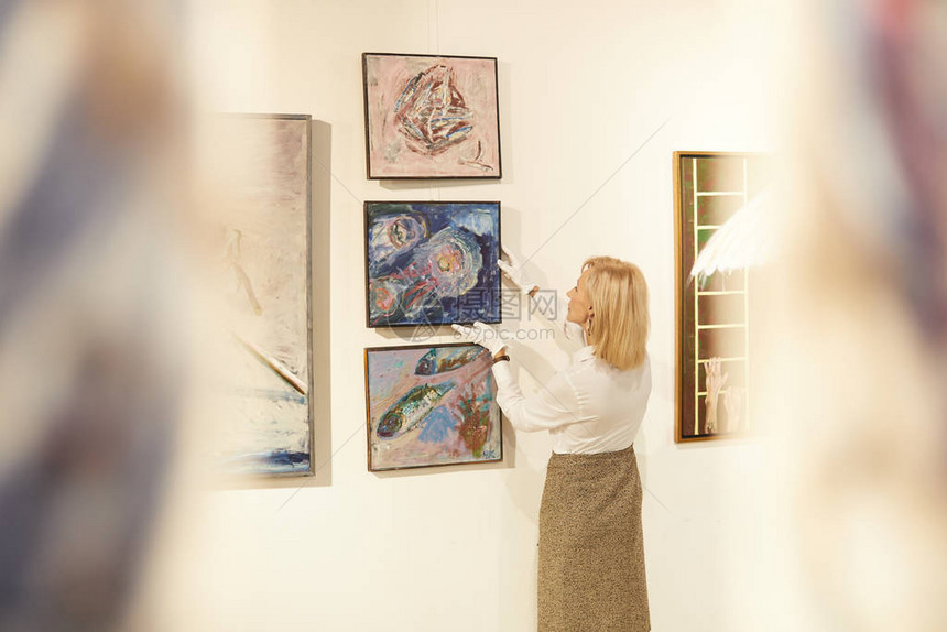 女艺术专家在美术馆或博物馆复制空间工作时挂绘图片