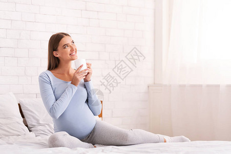 快乐的孕妇在早睡时喝咖啡图片