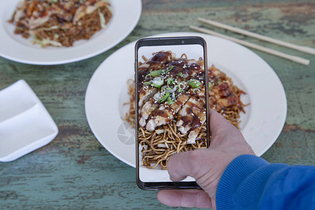 男孩用手机拍摄亚洲美食盘子的手图片