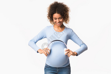 孕妇在怀孕白种背景附近戴耳机的预期妇女将拥有耳机图片