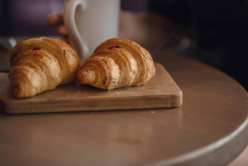 卡布奇诺咖啡与美丽的拿铁艺术和羊角面包在桌子上的木制背景早上的完美早图片