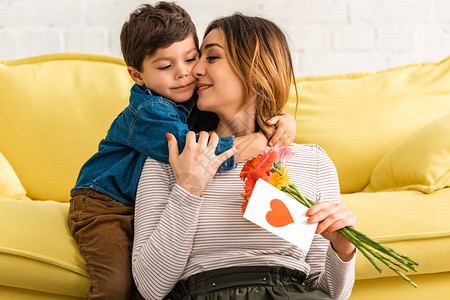 可爱的男孩拥抱妈拿着鲜花的母亲和母亲用图片