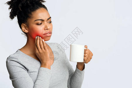 敏感的牙齿黑人女孩喝咖啡摸脸颊特图片