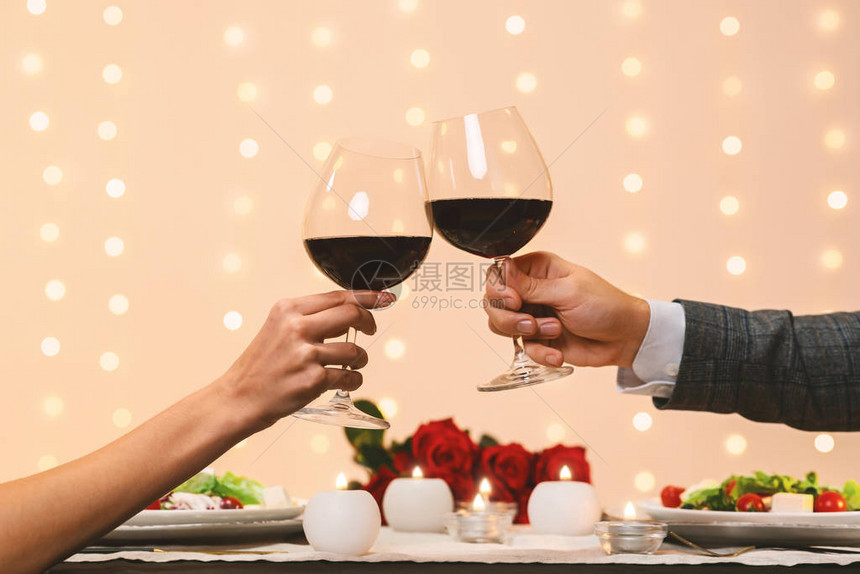 为我们干杯浪漫情侣在餐厅的约会时拿着两杯红葡萄酒图片