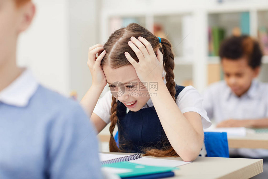 紧张的女学生坐在桌子上头抬着头不知如图片