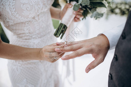 美丽的女孩新娘穿着白色婚纱戴上新郎手指上图片