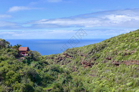 一座孤零的小房子坐落在绿色森林中的悬崖上图片