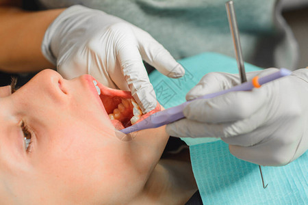 在牙科办公室的男孩检查新牙齿和治疗有缺陷的牙齿图片