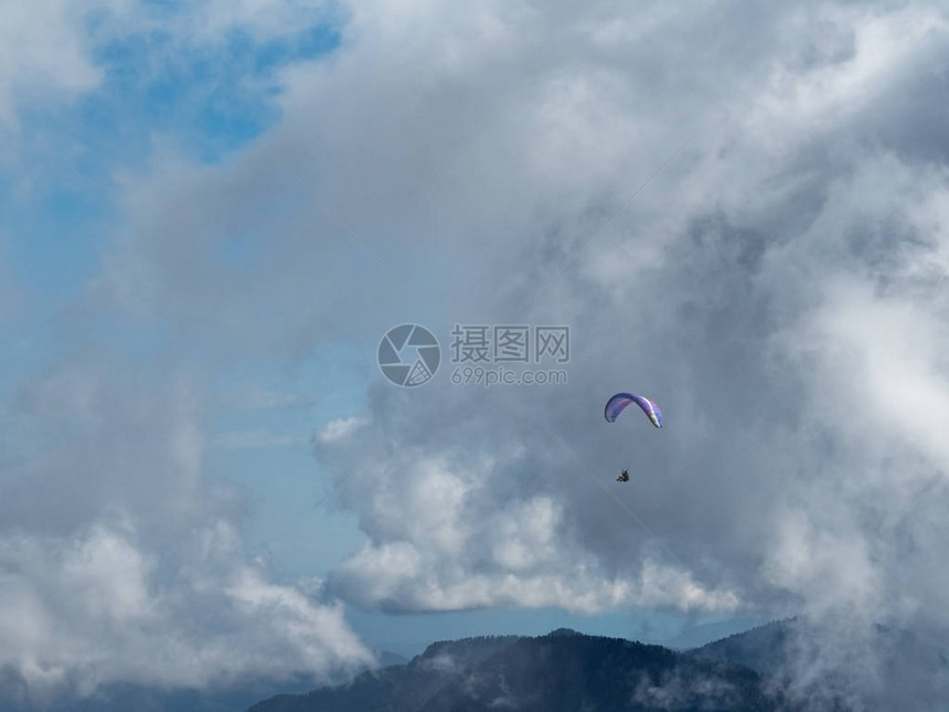 一个人在山上飞着滑翔伞对图片