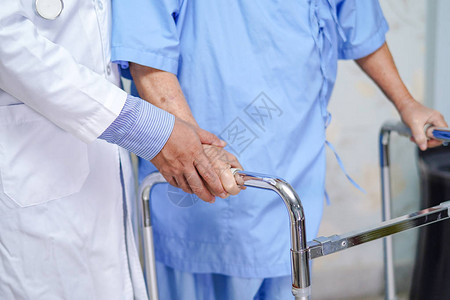 医生帮助亚洲老年或老年妇人患者在护理医院病房与步行者同行图片