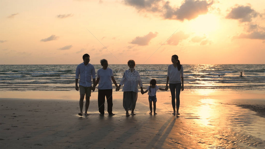 假期概念大家族在海滩上手牵行图片