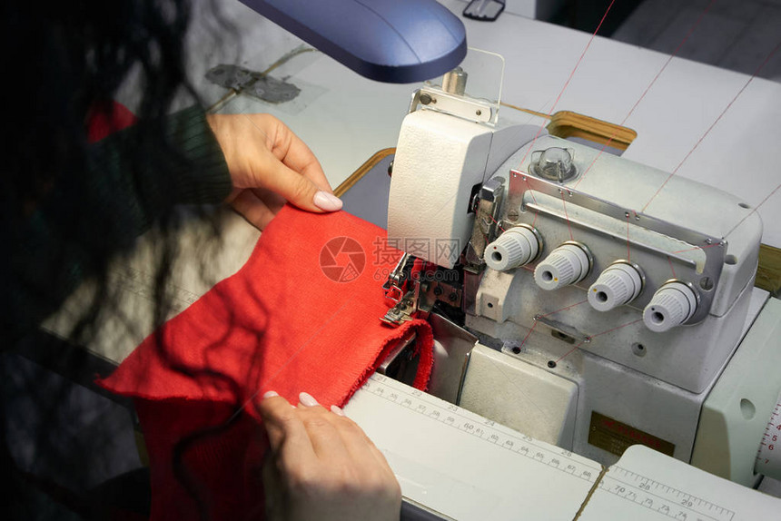 年轻女子在车间使用专业包缝机裁缝店的修边包图片