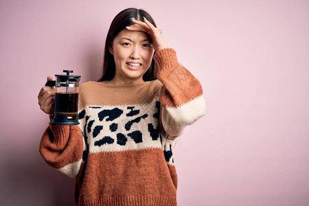 年轻的亚洲女用法式咖啡机在粉红色的背景下制作一杯咖啡图片