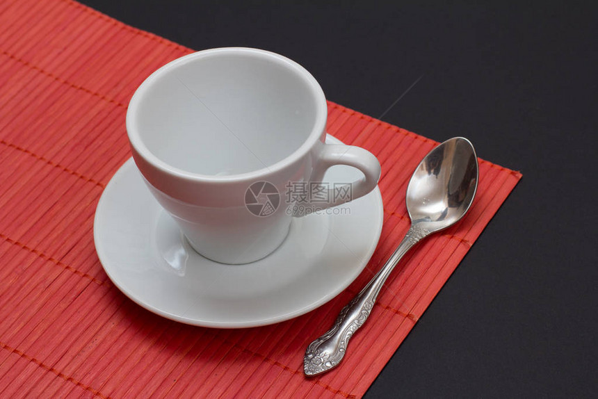 白咖啡杯茶碟和不锈汤匙在红竹餐巾上图片