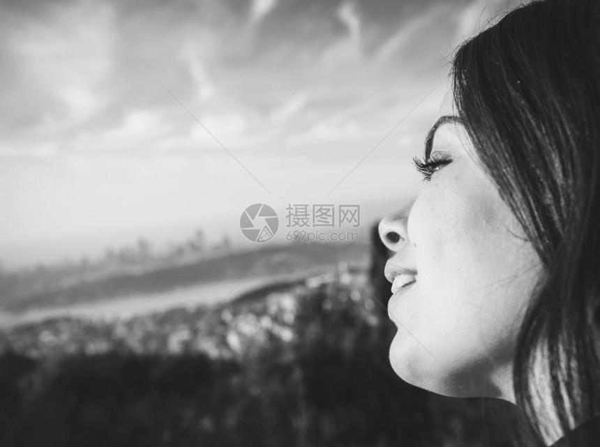 年轻女孩的黑白肖像lookig到背景中的大城市图片