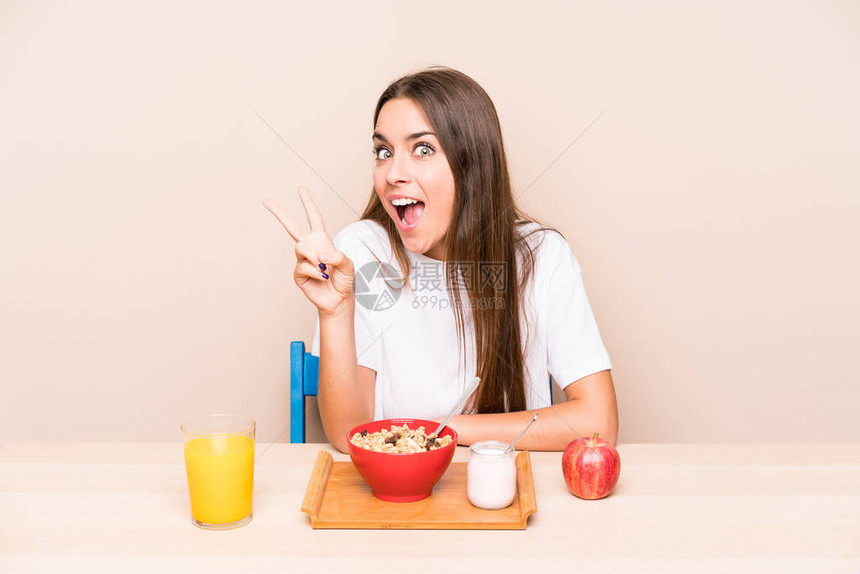 吃早餐的年轻白人妇女快乐而无忧虑地用手指展图片