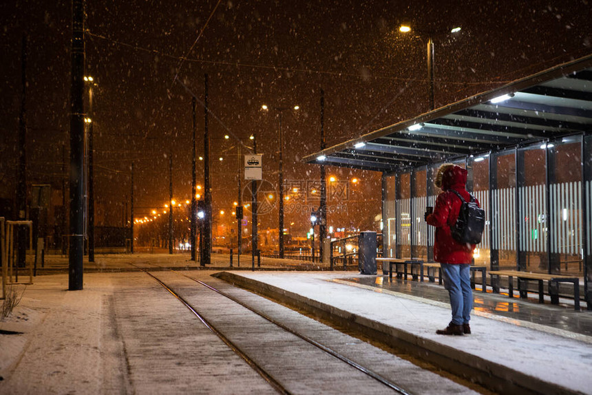 站在公共汽车电上站着的红色冬季大衣男子停止等待公图片