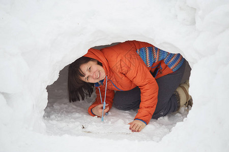 可爱的小caucasian小男孩铲雪在院子里的雪和firtr背景图片