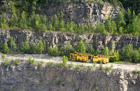 用于提取花岗岩的黄色机器站在花岗岩采石场岩图片