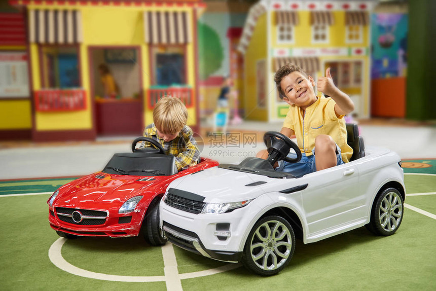 快乐的小男孩在娱乐中心玩得开心孩子们在游戏中心驾驶玩具车儿童休闲中心现代图片