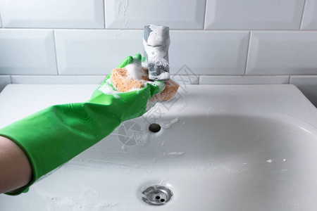 用绿色橡胶手套清洁家用浴室黄色海绵和液体泡沫洗涤剂中的水槽概图片