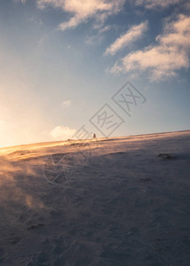 冬天日落时爬上白雪皑的山顶的人图片