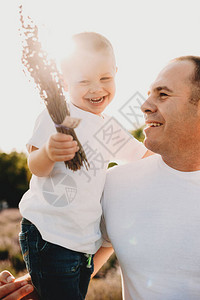 一个笑儿子被他父亲抱住的好景象父亲被太阳和熏图片