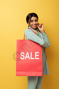持有购物袋的美籍非洲妇女持销售书信和在黄色图片