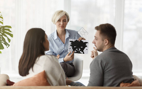 婚姻治疗专业心理学家在坐办公室的家庭咨询期间展示墨迹图片测试夫妇图片