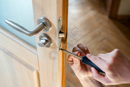 木匠修理门锁安装门把手杂工拧紧门铰链修理工的手有螺丝刀的锁匠将图片