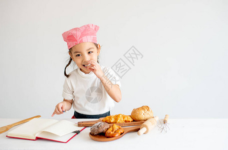 亚洲小厨师女孩通过挑点食物和吃白底饭背景图片