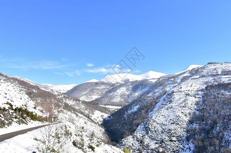 与雪山和蓝天的冬天风景山路山谷和森林Ancares图片