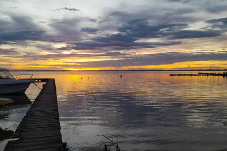 水湖中日出木质浮舟黄天空中图片