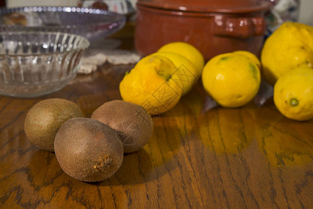 木桌上的三个猕猴桃和几个柠檬图片