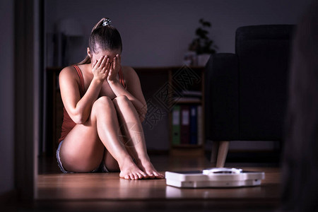 对减肥节食或体重增加有压力的女饮食失调厌食症或贪食症的概念年轻的女孩哭着坐在地板上背景图片