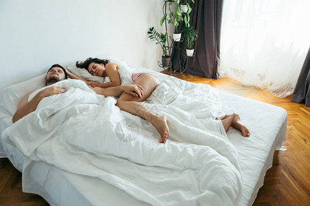 夫妇睡在床上有白色床图片