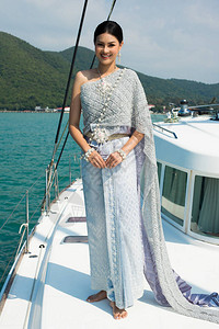 蓝灰色泰国传统服装的亚裔女与珠宝首饰在绿大洋美丽的天空中Luxury图片