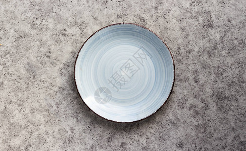 灰色背景上的空陶瓷蓝色盘子图片