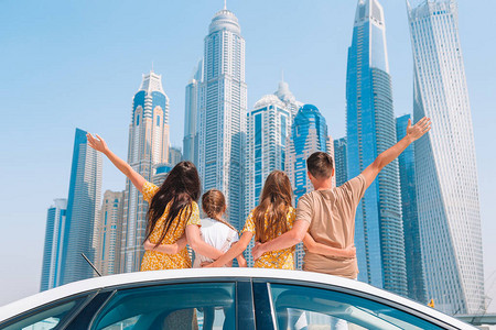 在迪拜摩天大楼背景下四人家庭图片