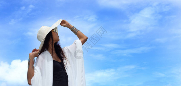 身穿大帽子黑泳衣的MixRicleTannedSkin女在蓝色热带天空和云层的夏季海洋背景图片